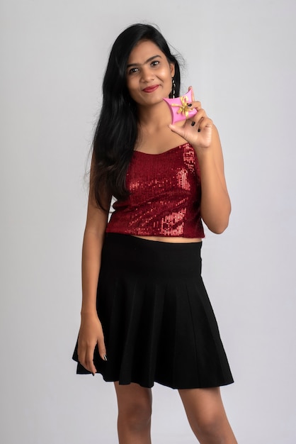 Portrait of a pretty young girl posing with gift box on grey