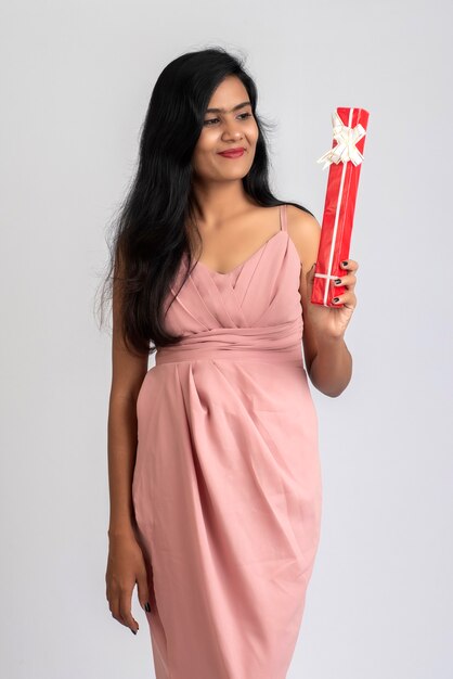 Portrait of a pretty young girl posing with gift box on grey.