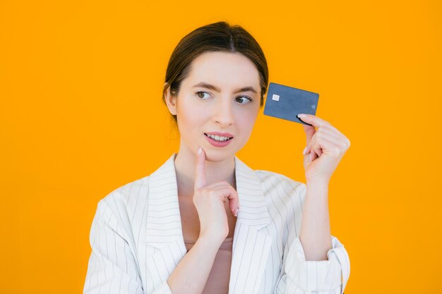 Portrait of a pretty young woman holding credit card at her face