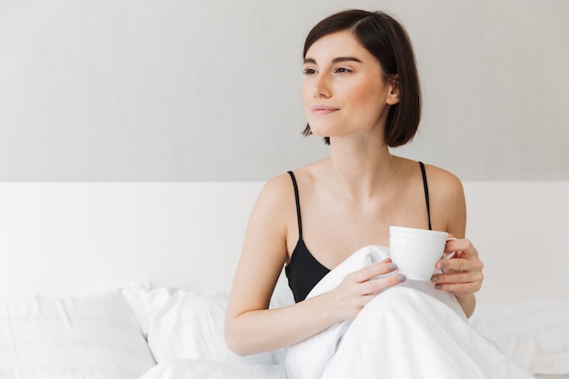 Portrait of a pretty young woman holding cup of coffee