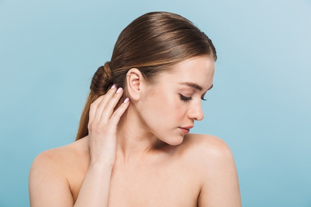 Portrait of a pretty young woman posing isolated over blue wall.