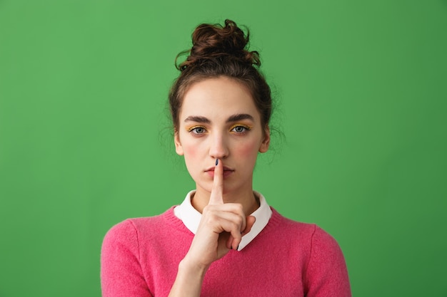 Photo portrait of a pretty young woman standing isolated, showing silence gesture