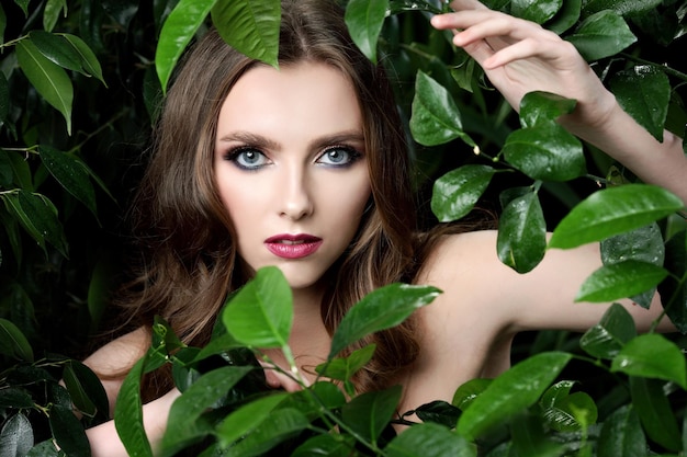 Portrait of pretty young woman standing near leaves