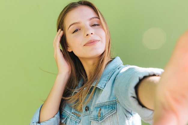 Photo portrait of a pretty young woman taking self portrait on green background