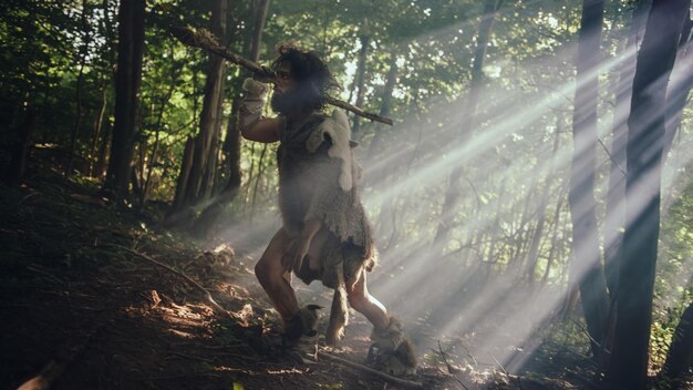 Photo portrait of primeval caveman wearing animal skin and fur hunting with a stone tipped spear in the prehistoric forest primitive neanderthal hunter ready to throw spear in the jungle