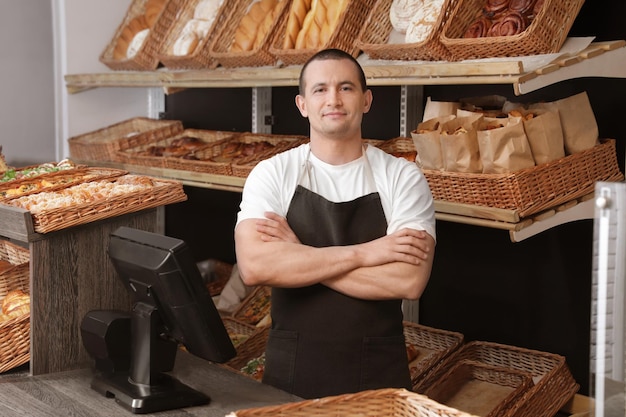 Portrait of professional baker at cashier desk near showcase in store