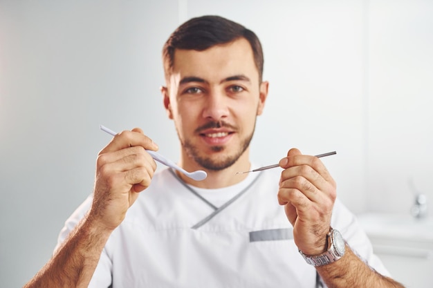 Portrait of professional dentist with equipment that standing indoors