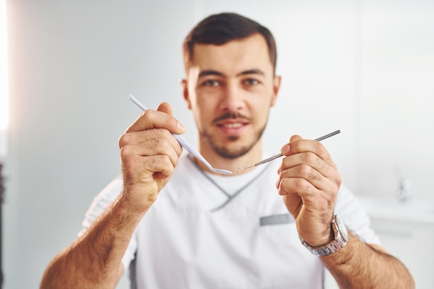 Портрет профессионального дантиста с оборудованием, стоящим в помещении