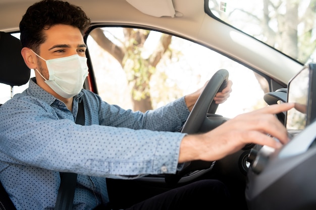 Ritratto di pilota professionista maschio che indossa la maschera per il viso e utilizzando il sistema di navigazione gps in auto. concetto di trasporto. nuovo concetto di stile di vita normale.