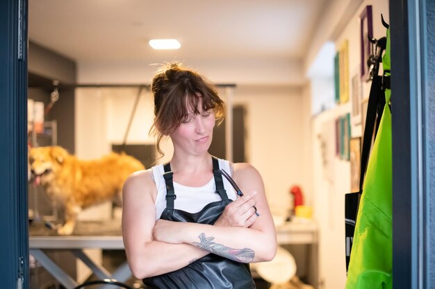 Photo portrait of professional pet hairdresser hipster woman with tattoos while standing at the door of her beauty salon for animals