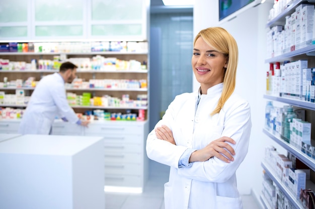 Portrait of professional woman pharmacist proudly standing in pharmacy shop or drugstore.