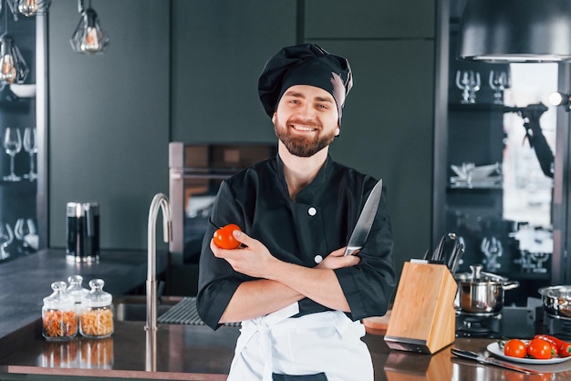 Portrait of professional young chef cook in uniform that posing for camera on the kitchen