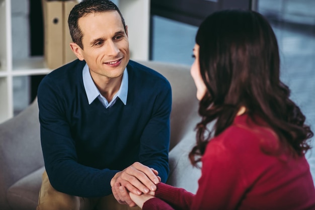 Portrait of psychologist sounseling patient holding hands and looking at each other