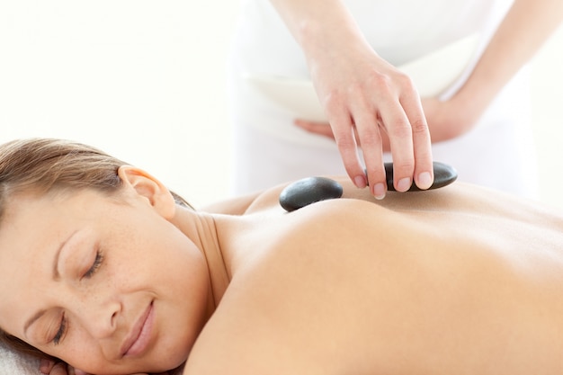 Portrait of a radiant woman having a massage with stones 