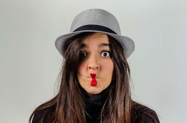 Foto ritratto di una vera ragazza che gesticola con le labbra rosse su uno sfondo grigio