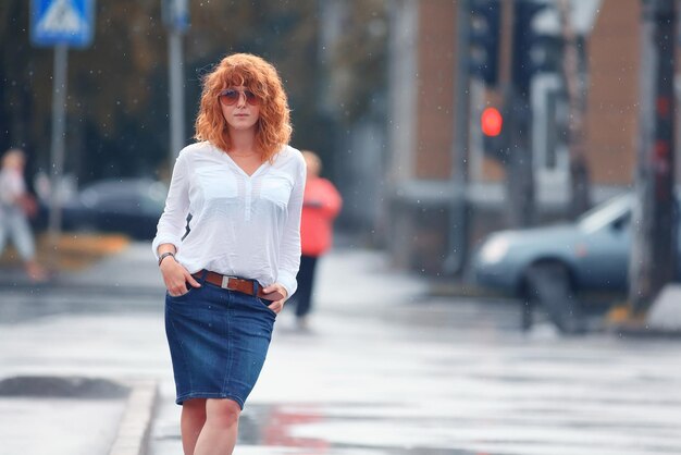 Portrait of red-haired happy woman in the rain