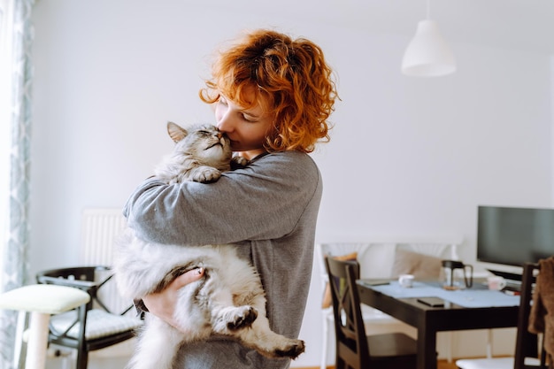 Portrait redhaired curly young woman with beloved fluffy domestic cat