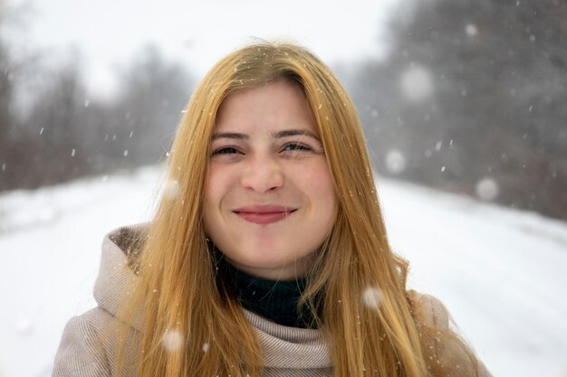 ぼやけた雪の背景を持つ彼女の顔にそばかすのある赤髪の少女の肖像画