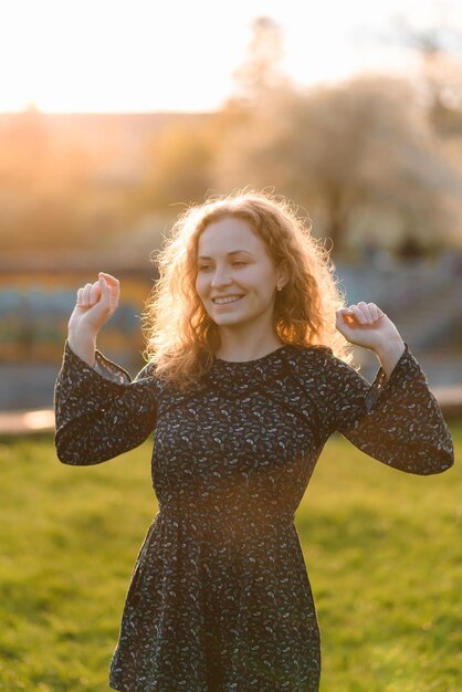 Photo portrait of a redhaired woman is dancing at sunset in the park