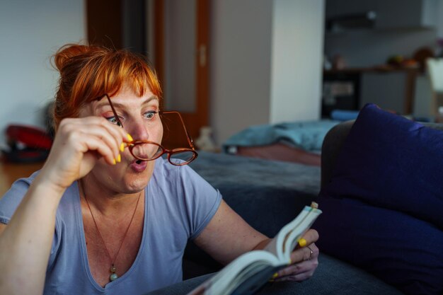 Foto ritratto di una donna dai capelli rossi che legge un romanzo