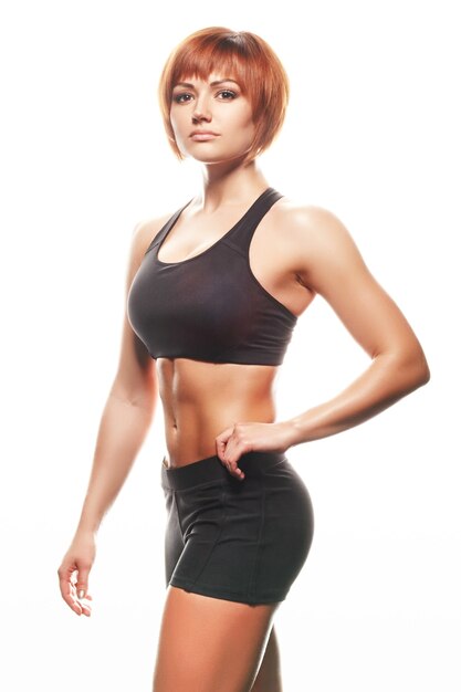 Portrait of redhead woman in sportswear. Studio shot, isolated, white background