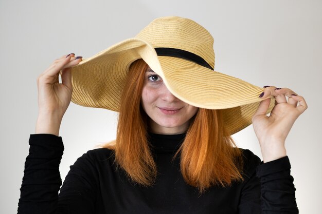 Portrait of redhead woman in a yellow straw hat.