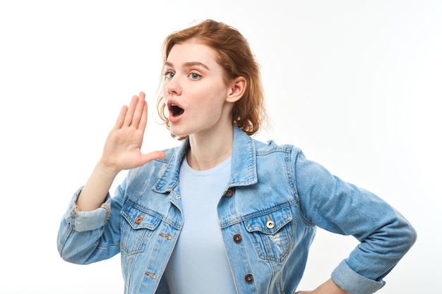 Photo portrait of redhead young woman screaming into her palms on white studio background important information news concept