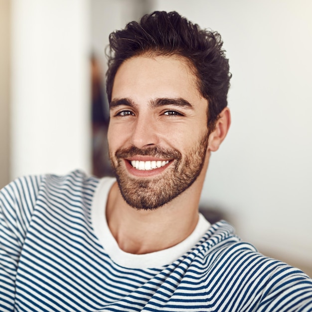 portrait relax and man with smile in home break and happiness for weekend in living room calm and couch lounge comfortable and person with joy for rest morning and confident in apartment