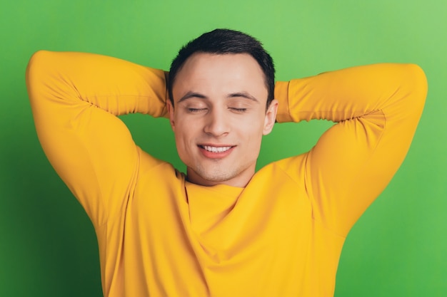 Portrait of relaxed dreamy nice guy hands head sleep on green background