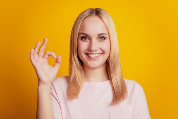 Portrait of reliable adviser pretty girl show okey gesture on yellow background