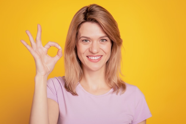 Portrait of reliable promoter lady show okey sign toothy beaming smile on yellow background