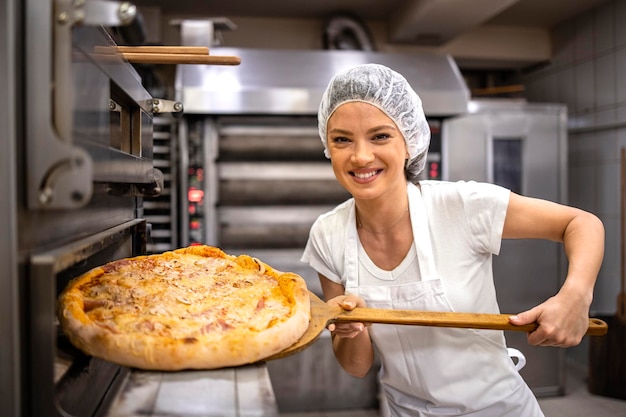 Portrait of restaurant chef taking pizza from the oven in pizzeria