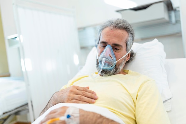 Photo portrait of retired senior man breathing slowly with oxygen mask during coronavirus covid19 outbreak old sick man lying in hospital bed getting treatment for deadly infection