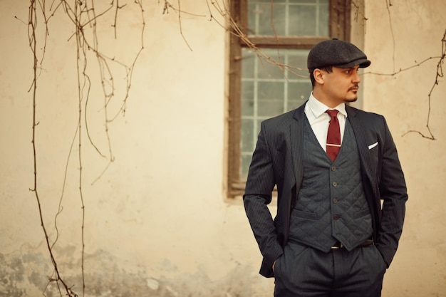 Portrait of retro 1920s english arabian business man wearing dark suit tie and flat cap