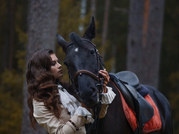 Portrait of a rider in a retro suit and her black horse.