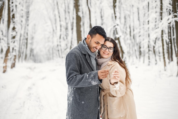 Portrait of a romantic couple holding a sparkle in winter forest