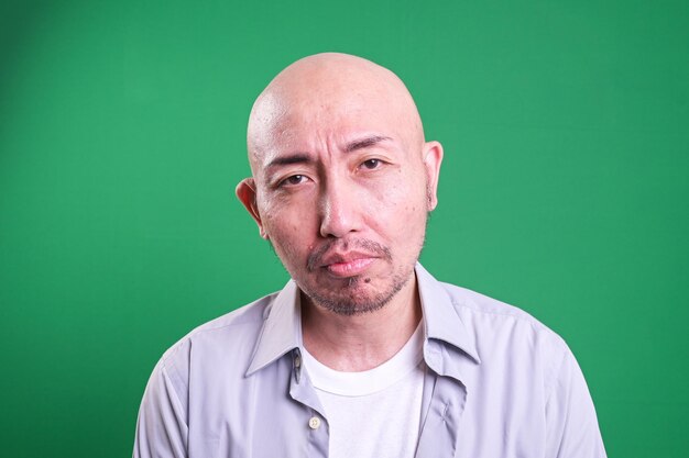 Photo portrait of sad asian man isolated on green background mental health concept