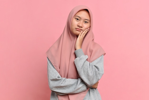 Portrait of sad Asian muslim female against pink background. sadness hopeless