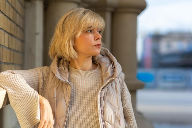 Portrait of sad caucasian adult woman posing in park blurred city at background side view concept of