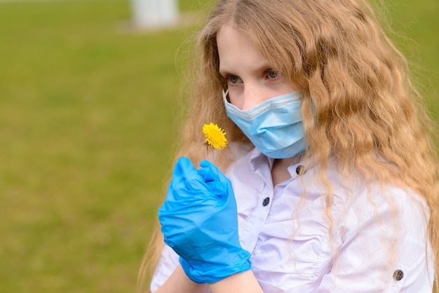 Portrait of sad Caucasian girl in face mask at the city and in the park outdoor. Coronavirus social distance quarantine.