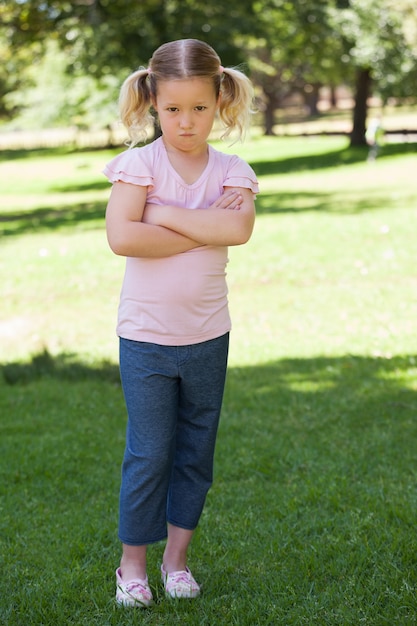 Photo portrait of a sad girl with arms crossed at park