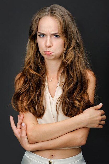 Portrait of sad or offended girl with pouted lips isolated on gray background