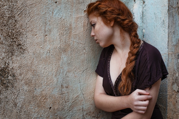 Portrait of a sad red-haired girl, sadness and melancholy in her eyes