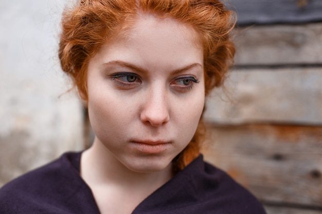 Photo portrait of a sad red-haired girl, sadness and melancholy in her eyes