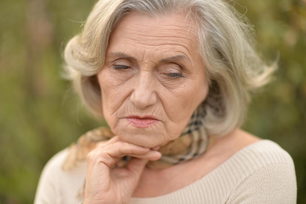 Portrait of sad senior beautiful woman in park