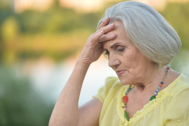 Portrait of sad senior beautiful woman in park