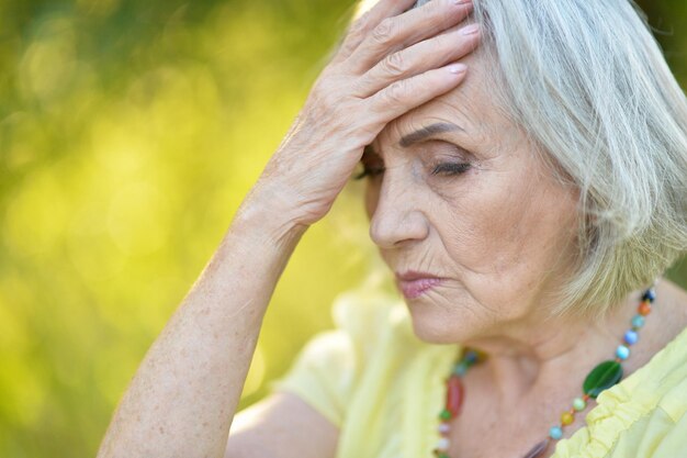 Portrait of sad senior beautiful woman posing in spring park