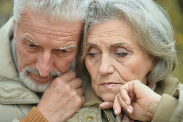 Portrait of a sad senior couple in autumn park