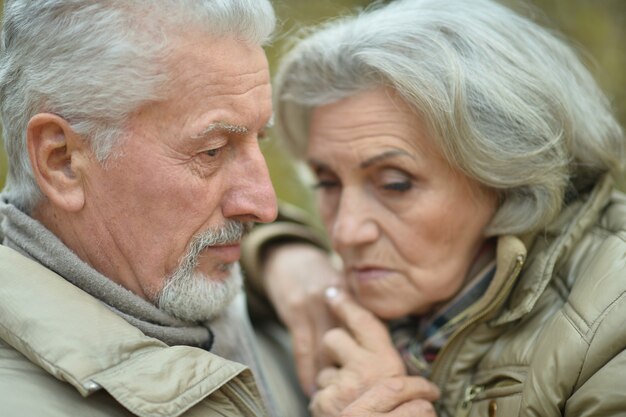 Portrait of a sad senior couple in autumn park