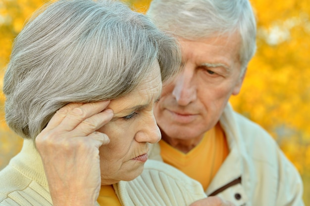 Portrait of a sad senior couple in autumn park